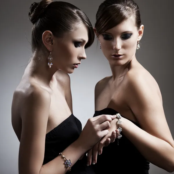 Две красивые женщины в черном платье с драгоценностями — стоковое фото