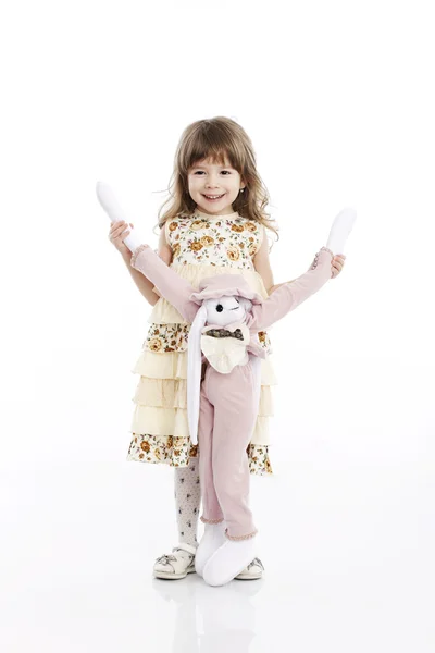 Porträtt av en leende liten flicka som leker med en leksak kanin — Stockfoto