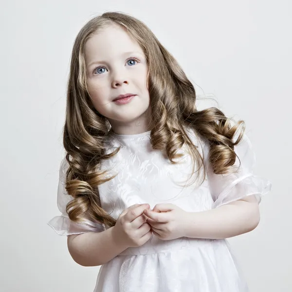 Retrato de una hermosa niña con un vestido blanco y un velo sobre un fondo blanco — Foto de Stock