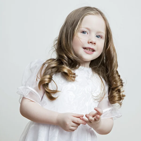 A fehér ruha és fátyol fehér háttéren egy gyönyörű kislány portréja — Stock Fotó