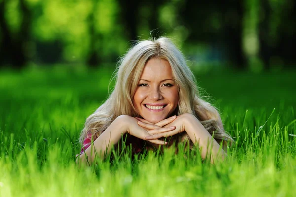 Блондинка лежить на зеленій траві — стокове фото