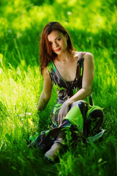 坐在绿草地上的黑发 — 图库照片