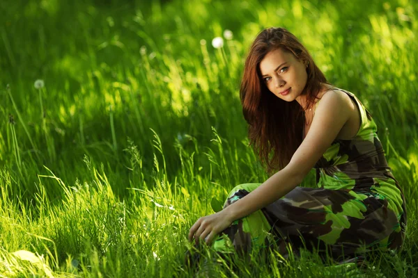 Bruneta sedí na zelené trávě — Stock fotografie