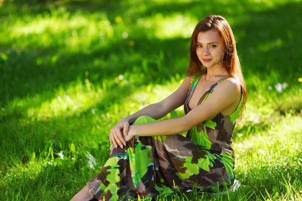 Брюнетка сидит на зеленой траве — стоковое фото