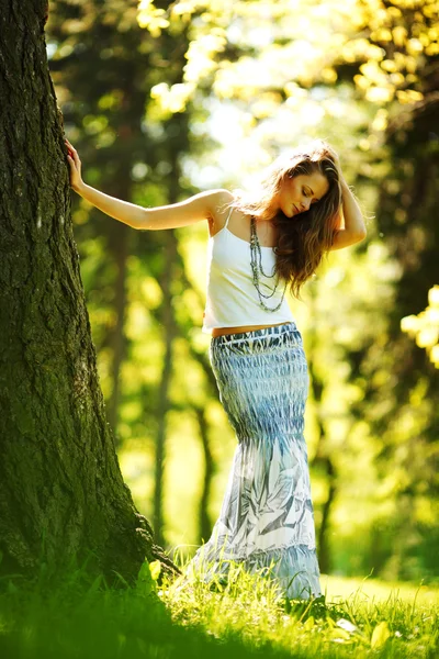 Chica de pie junto a un árbol — Foto de Stock