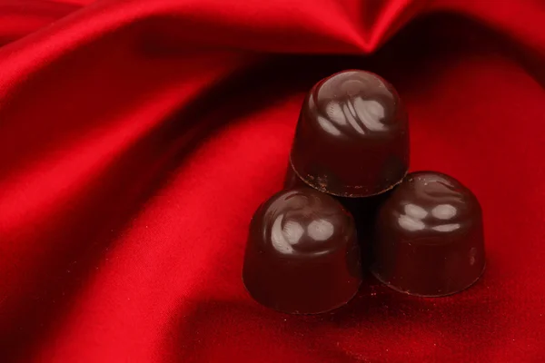Čokoládové bonbóny na červené saténové — Stock fotografie