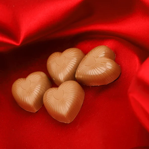 Snoep harten op rood satijn — Stockfoto