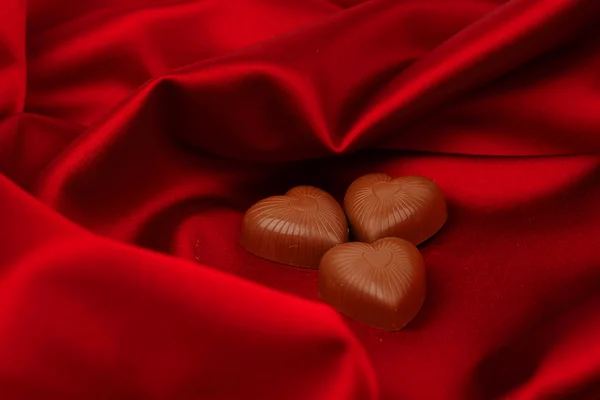 Конфеты сердца на Красная атласная — стоковое фото