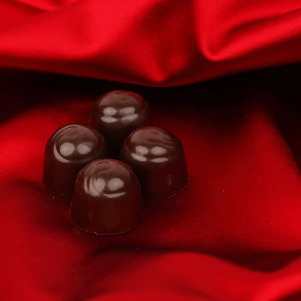 Dulces de chocolate en satén rojo — Foto de Stock