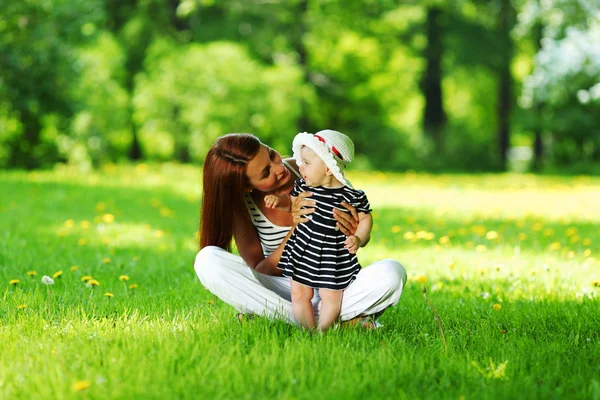 Moeder en dochter op het groene gras — Stockfoto