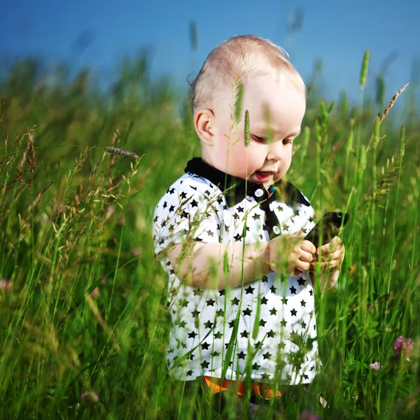 Мальчик в траве по телефону — стоковое фото