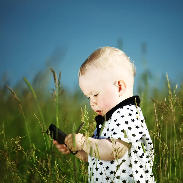 Jongen in gras gesprek via de telefoon — Stockfoto
