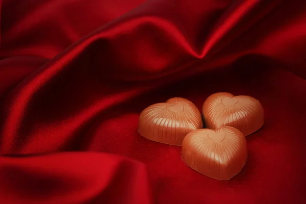 Corazones de caramelo en satén rojo — Foto de Stock