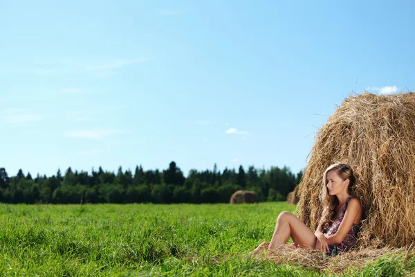 Menina ao lado de uma pilha de feno — Fotografia de Stock