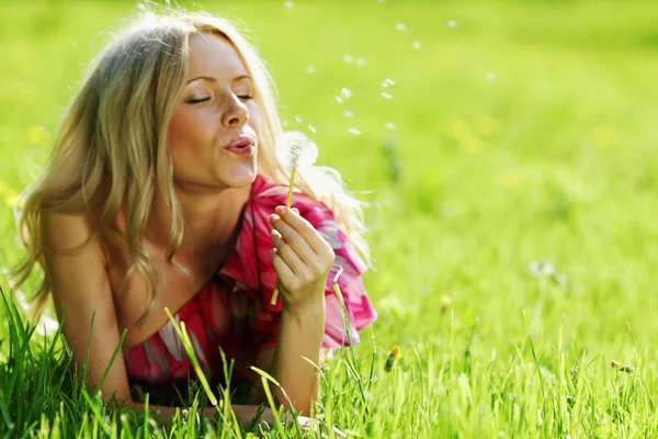 Girl blowing on a dandelion — Stock Photo, Image