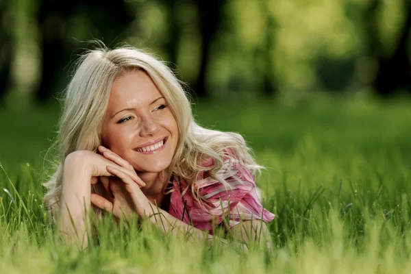 Blonde couchée sur l'herbe verte — Photo