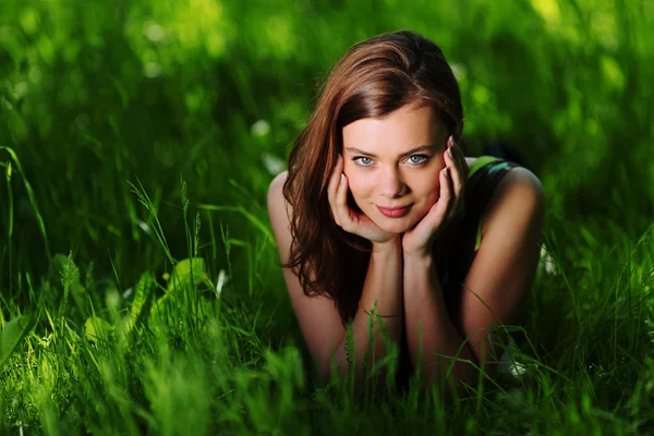 Брюнетка лежит на зеленой траве — стоковое фото