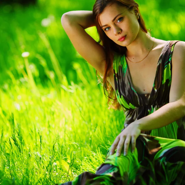 Morena sentado na grama verde — Fotografia de Stock