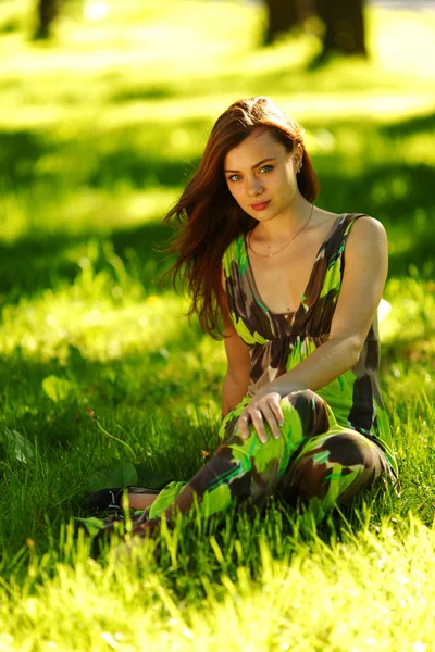 緑の芝生の上に座ってブルネット — ストック写真