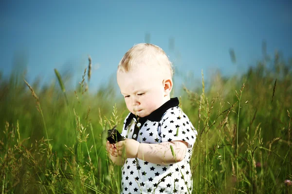 Niño en la hierba llamada por teléfono —  Fotos de Stock