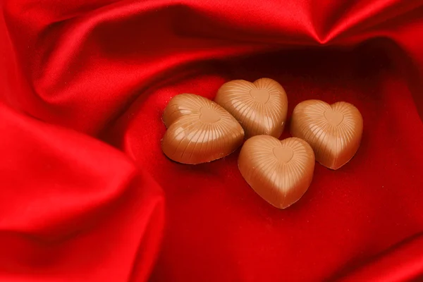 Corazones de caramelo en satén rojo — Foto de Stock