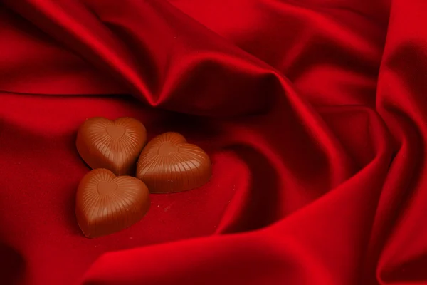 Serca cukierków na czerwono satyna — Zdjęcie stockowe