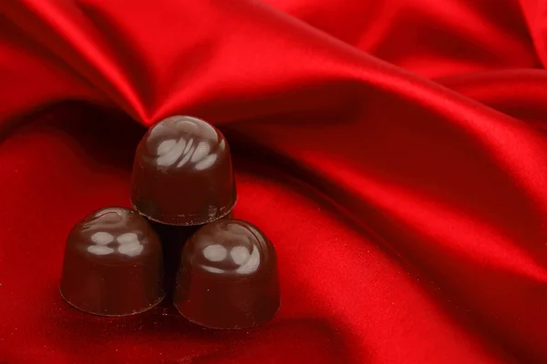 Cukierki czekoladowe na czerwono satyna — Zdjęcie stockowe