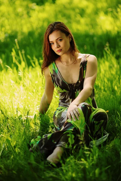 Brünette sitzt auf grünem Gras — Stockfoto