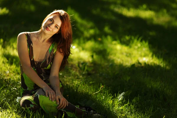Brunette zittend op groen gras — Stockfoto
