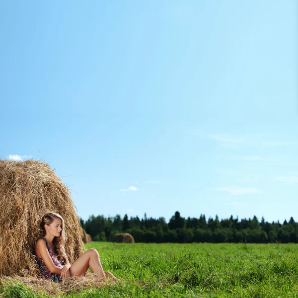 Menina ao lado de uma pilha de feno — Fotografia de Stock