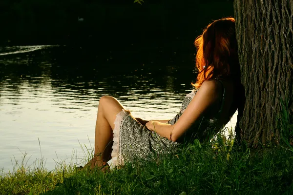 Girl sitting near river — Stock Photo, Image