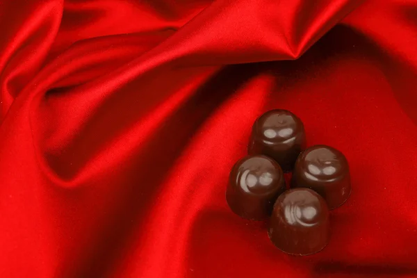 Čokoládové bonbóny na červené saténové — Stock fotografie