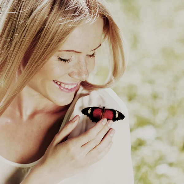 Kvinna leker med en fjäril — Stockfoto