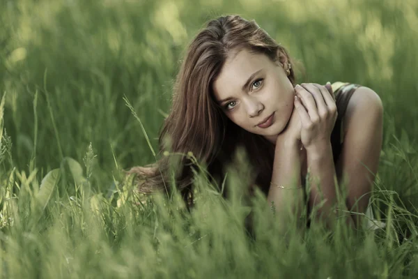 Brunette liggend op groen gras — Stockfoto