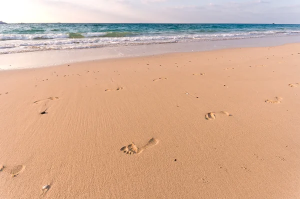 stock image Sandy beach with lots of footprints and a blue sky with clouds