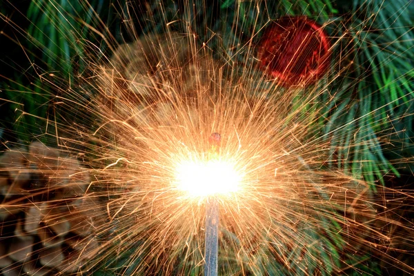 Burning (lit) sparkler in front of Christmas tree. — Stock Photo, Image