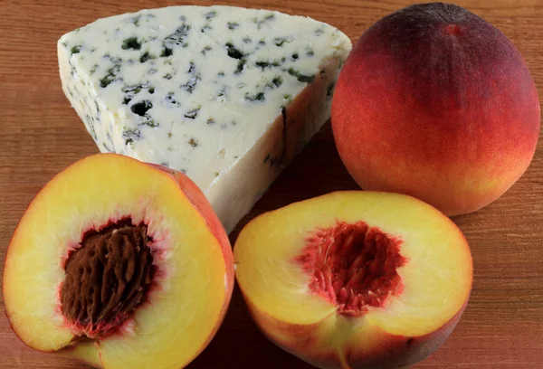 Фото голубого сыра из коровьего молока, подаваемого с нарезанным на половину персиком — стоковое фото