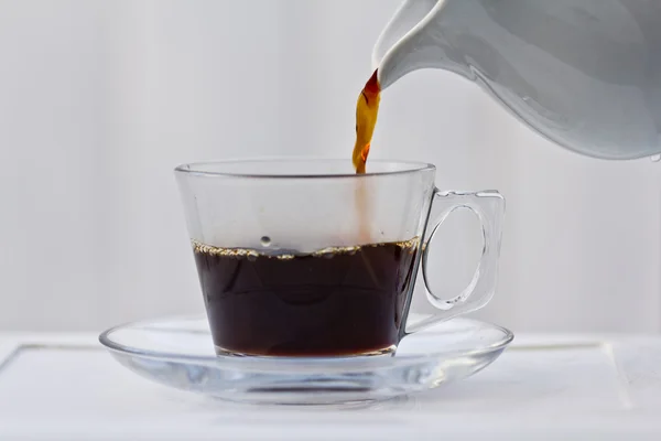 Pouring coffee into a half full cup