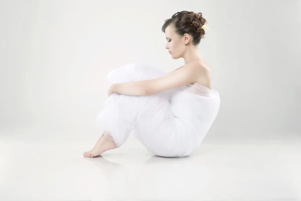 Приваблива молода жінка, загорнута в тканину, сидить на підлозі Стокове Фото