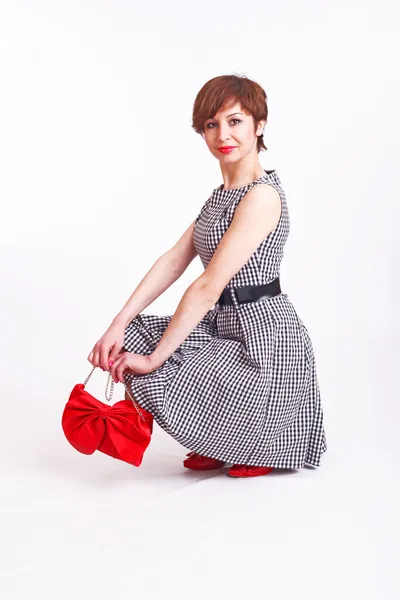 Portrait of a young beautiful woman in black&white dress, red shoes, red bag — Stock Photo, Image