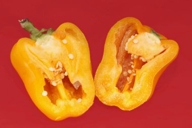 Yellow peppers paprika on red background clipart