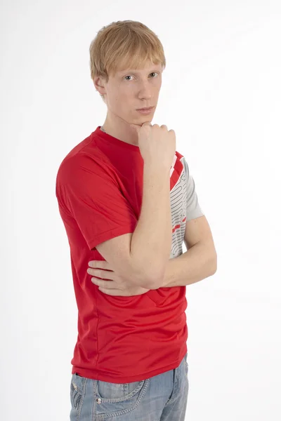 Genç adam beyaz zemin üzerine kırmızı bir tişört düşüncesinde — Stok fotoğraf