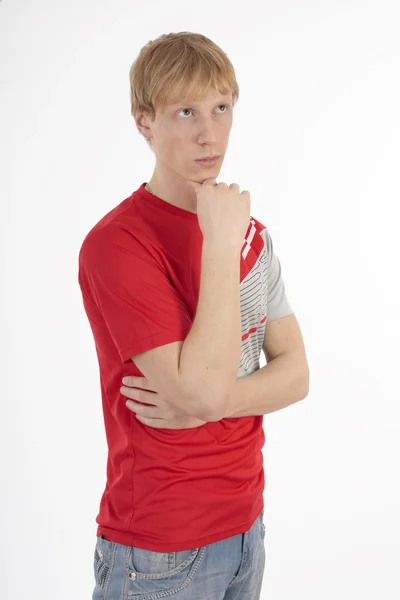 Genç adam beyaz zemin üzerine kırmızı bir tişört düşüncesinde — Stok fotoğraf