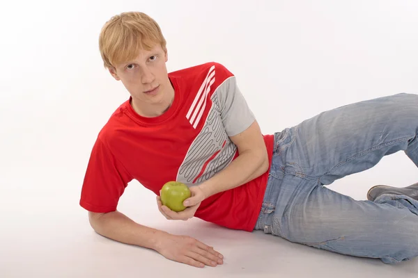 Jovem em uma camiseta vermelha segurando uma maçã verde — Fotografia de Stock