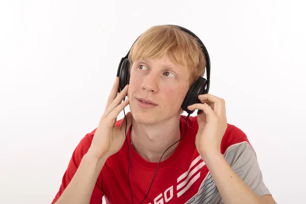 Jovem estudante menino vestido em vermelho ouvir música mp3, estúdio isolado no branco — Fotografia de Stock