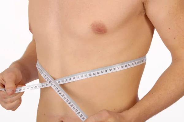 Homem muscular que mede a cintura no branco — Fotografia de Stock