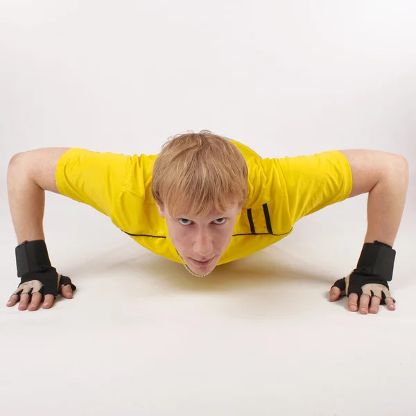 Unga fitness man göra push ups på golvet isolerat — Stockfoto