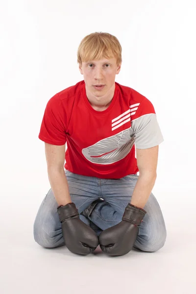 Serious young man in a red t-shirt with a boxing glove — Stock Photo, Image