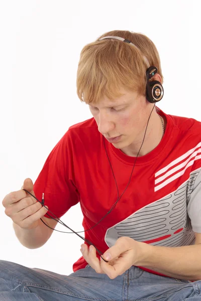 Mladý muž rozkrývá zamotaný sluchátka izolované — Stock fotografie