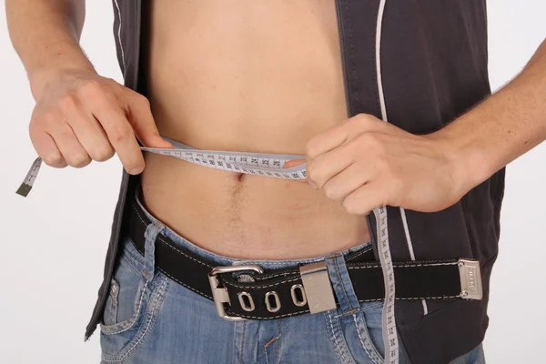 Hombre musculoso midiendo cintura en blanco — Foto de Stock